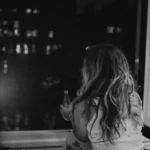 Woman looking out into the night through a window